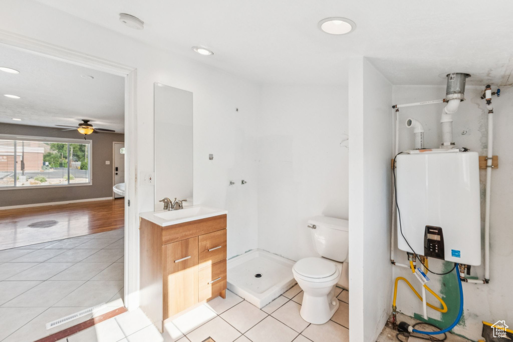Bathroom featuring tankless water heater, tile patterned floors, vanity, a stall shower, and a ceiling fan