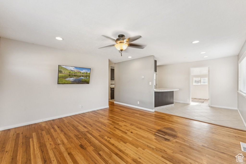 Unfurnished living room featuring light wood finished floors, ceiling fan, and recessed lighting