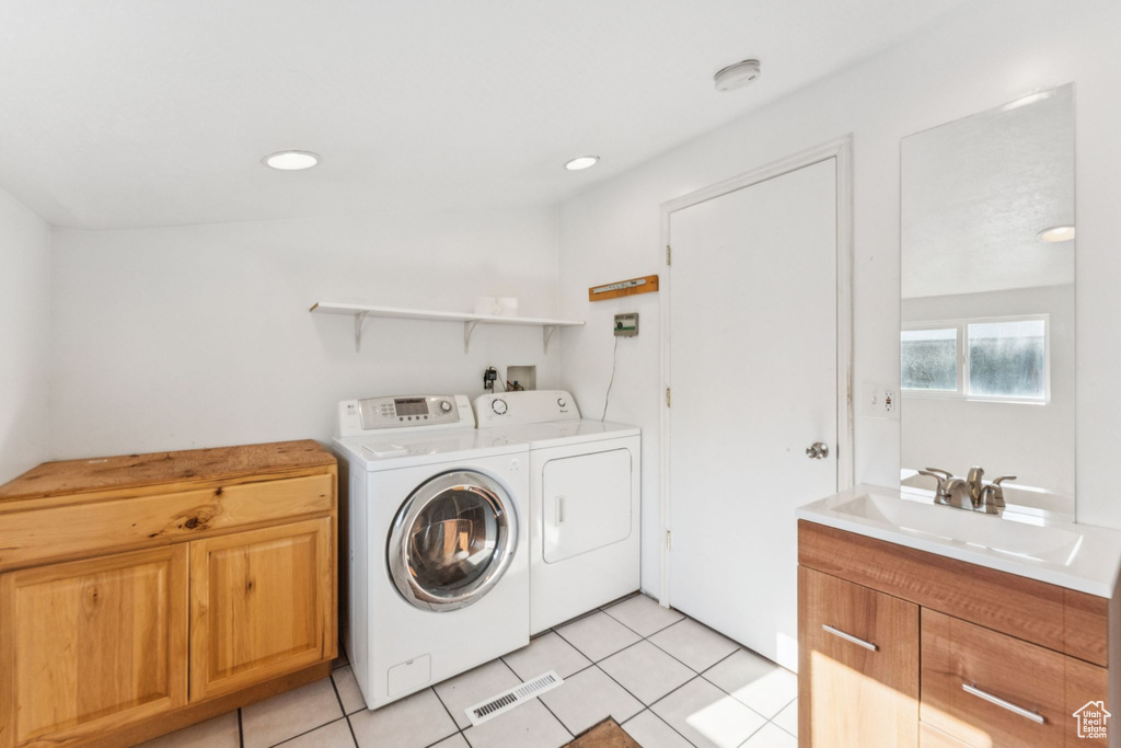 Laundry room with washing machine and dryer, light tile patterned flooring, cabinet space, and recessed lighting