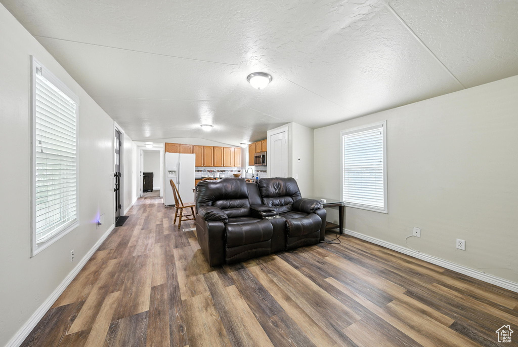 Living area with dark wood finished floors, lofted ceiling, and a textured ceiling