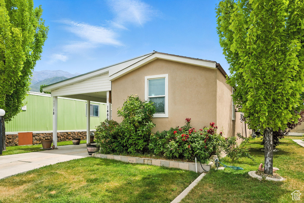 View of front of home with a front yard, a mountain view, stucco siding, and an attached carport