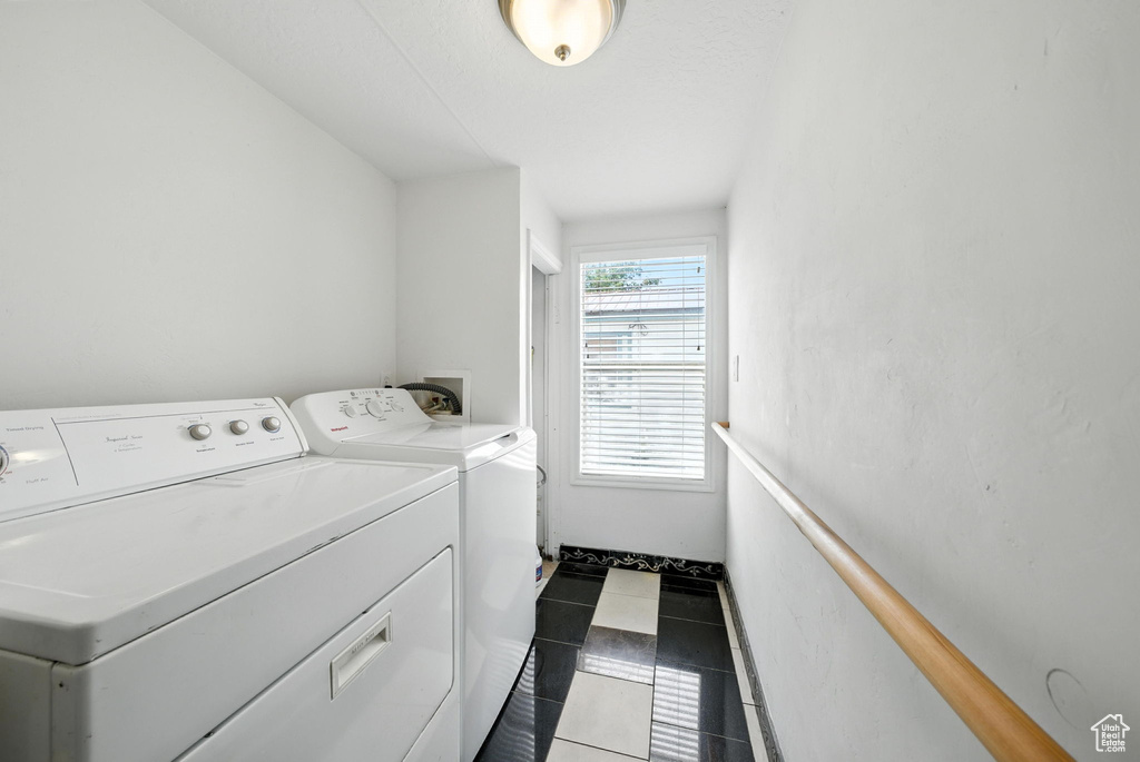 Washroom featuring washing machine and dryer and dark tile patterned floors