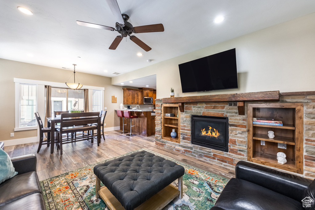 Living area featuring wood finished floors, ceiling fan, recessed lighting, and a fireplace