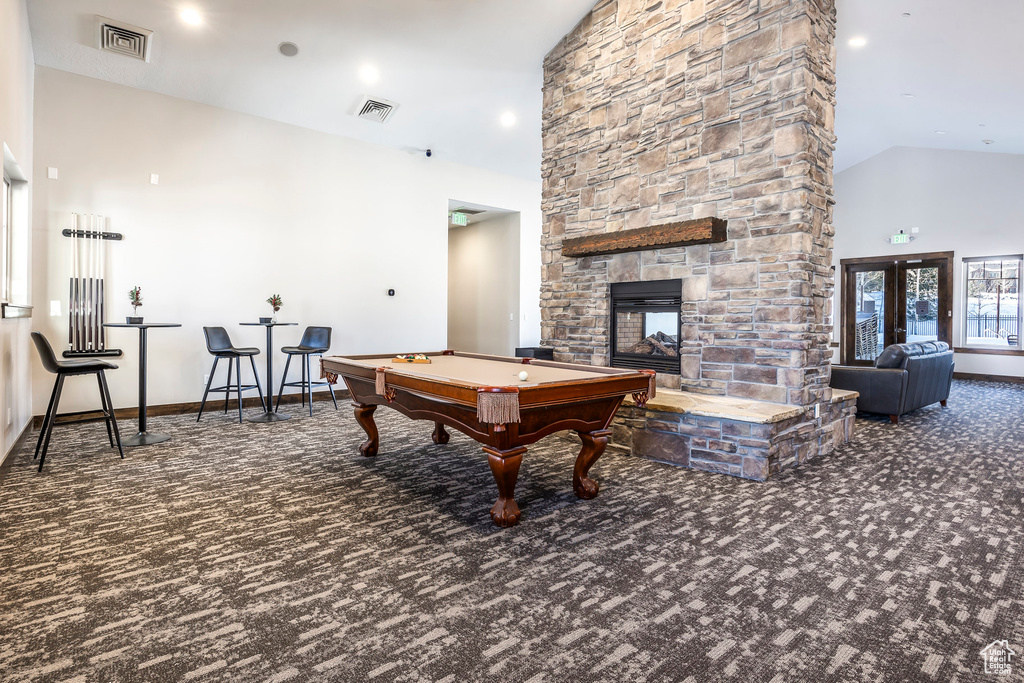 Rec room featuring carpet flooring, high vaulted ceiling, billiards table, and a stone fireplace