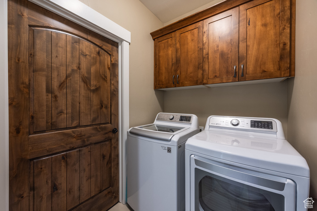 Washroom with washer and clothes dryer and cabinet space