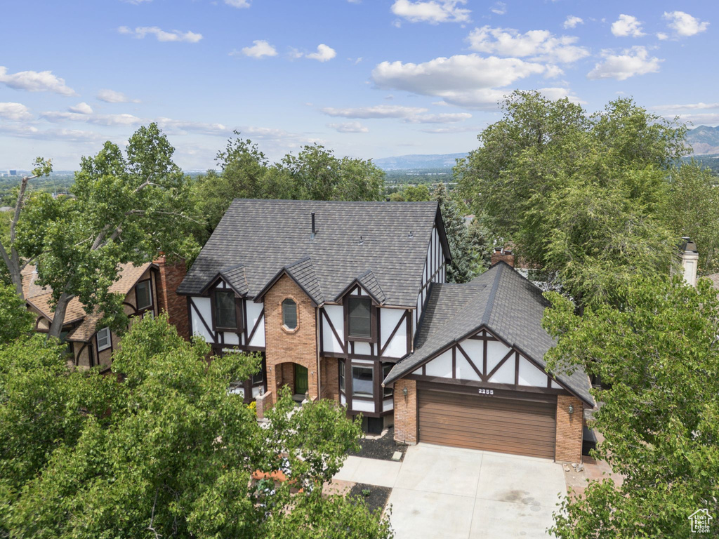 English style home with an attached garage, brick siding, and driveway