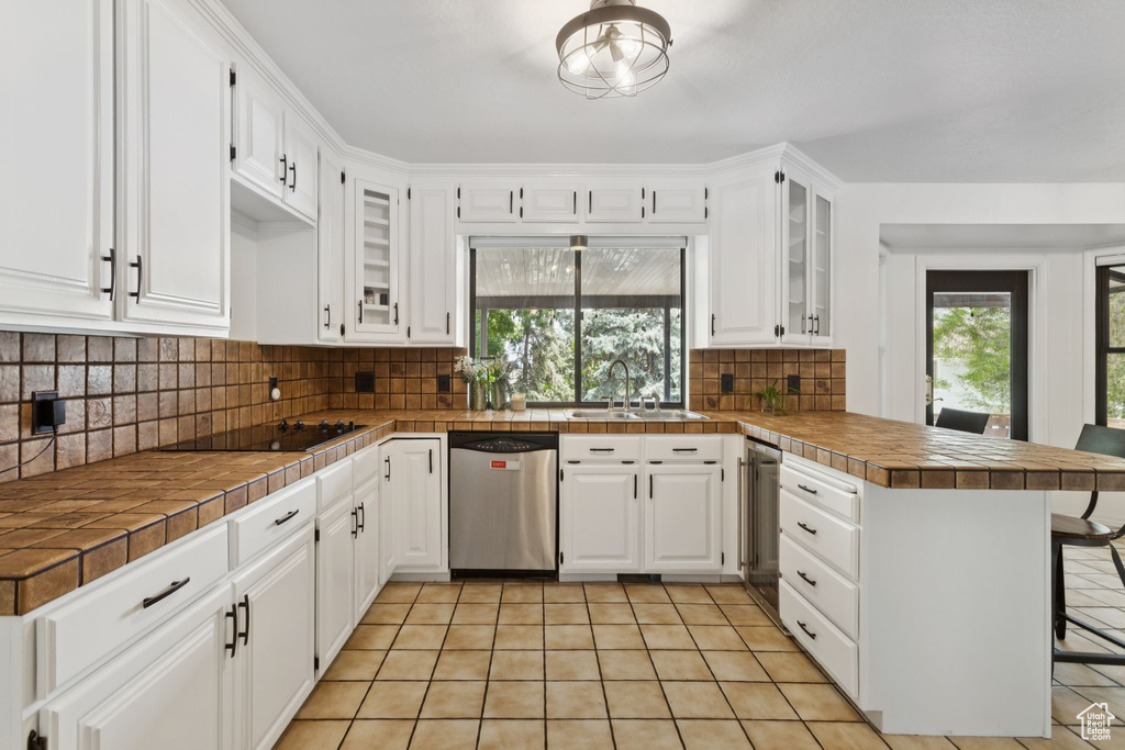 Kitchen featuring dishwasher, a peninsula, plenty of natural light, and black electric cooktop