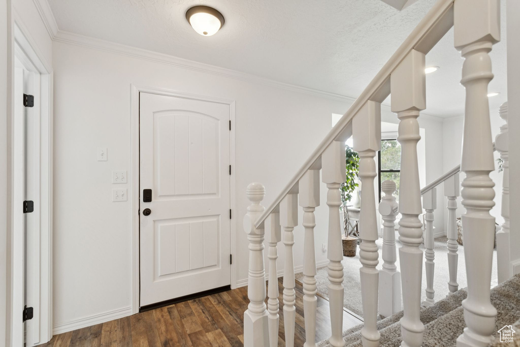 Entrance foyer featuring wood finished floors, crown molding, and stairway