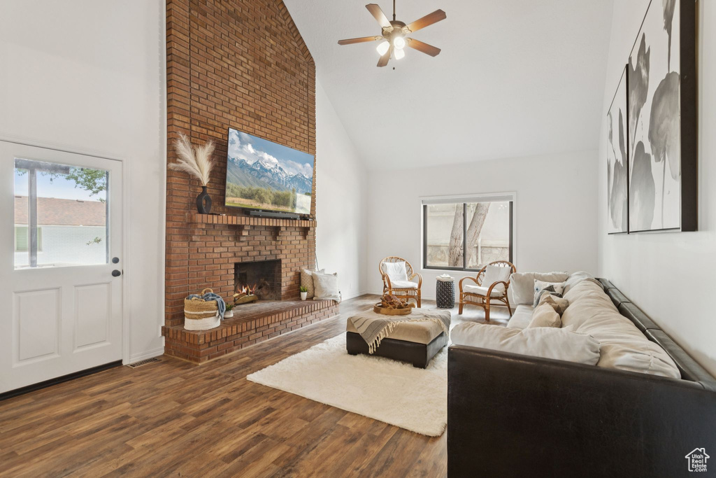 Living room with high vaulted ceiling, a ceiling fan, a fireplace, and wood finished floors