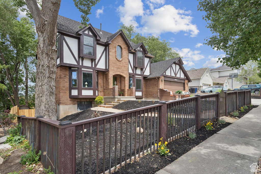 Tudor house featuring brick siding, a residential view, and roof with shingles