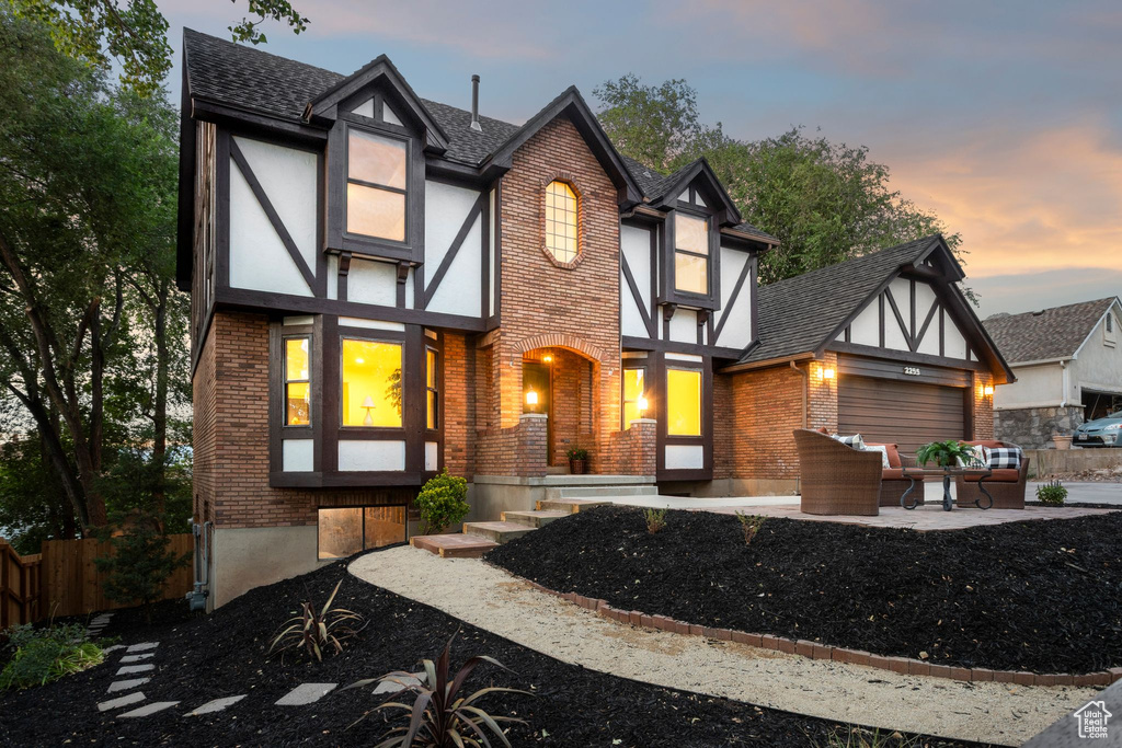 View of front facade featuring brick siding, roof with shingles, an attached garage, and stucco siding