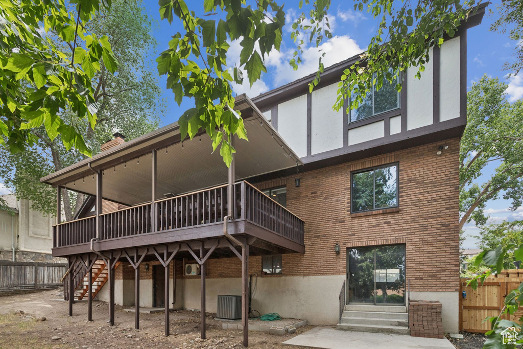 Back of property featuring brick siding, stairs, a deck, entry steps, and stucco siding