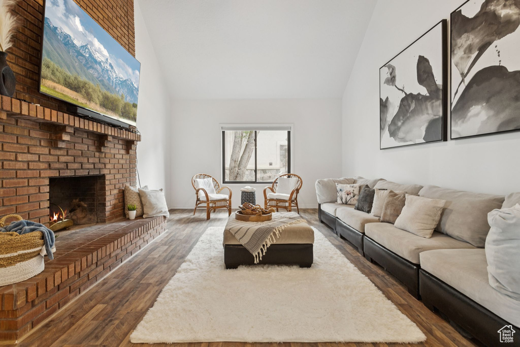 Living area with high vaulted ceiling, wood finished floors, and a fireplace