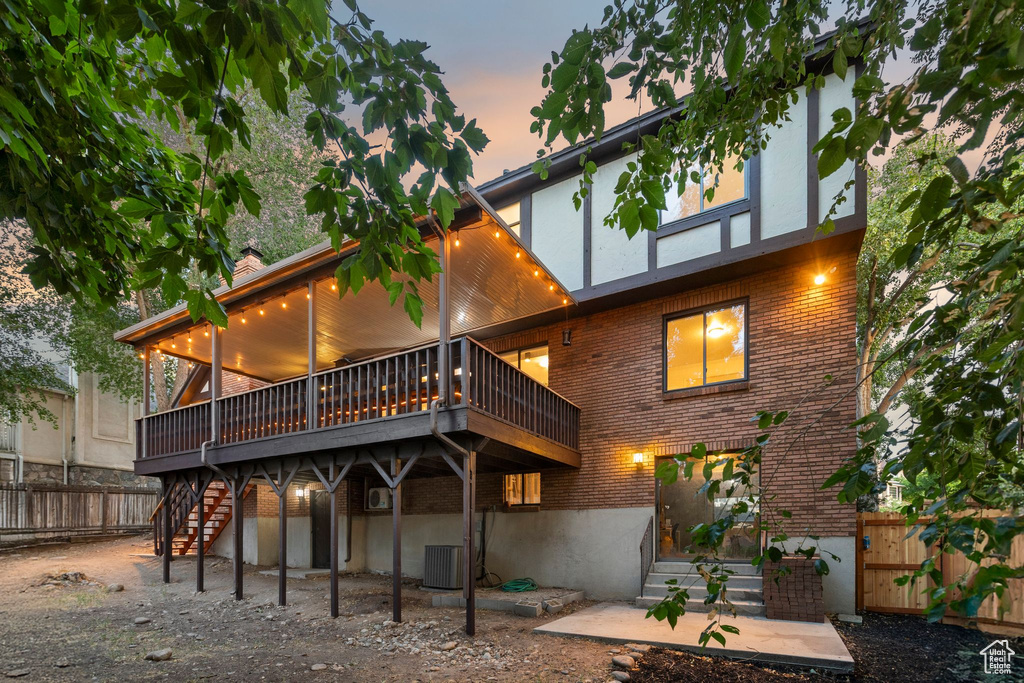 Rear view of house with stairway, brick siding, a wooden deck, stucco siding, and a gate