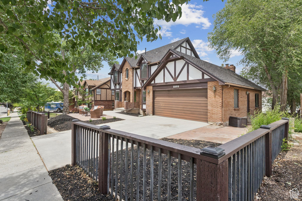 English style home featuring brick siding, an attached garage, a chimney, and driveway