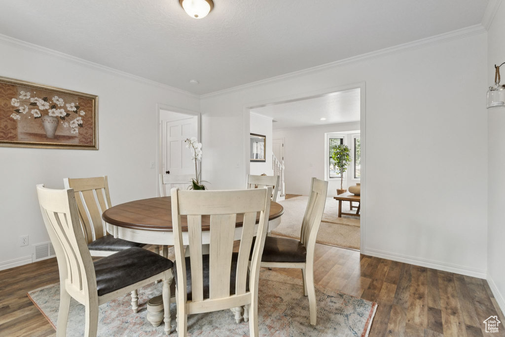 Dining area featuring wood finished floors and crown molding