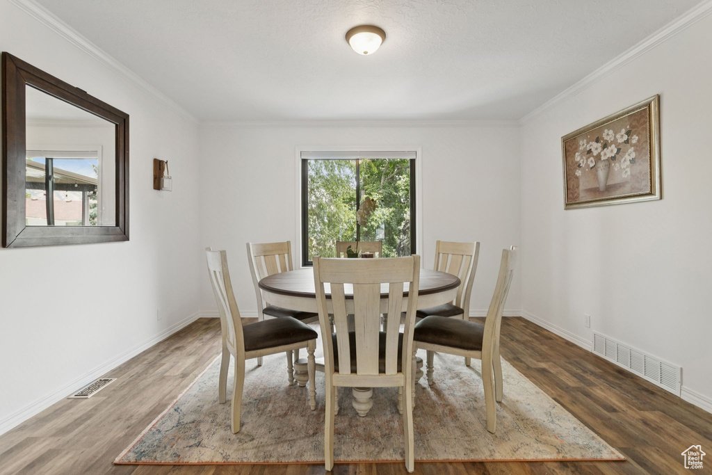 Dining area with wood finished floors and ornamental molding