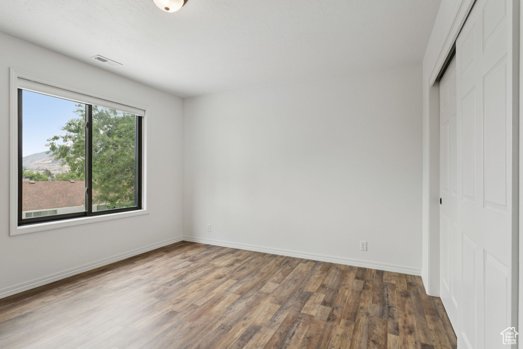 Unfurnished bedroom with wood finished floors and a closet