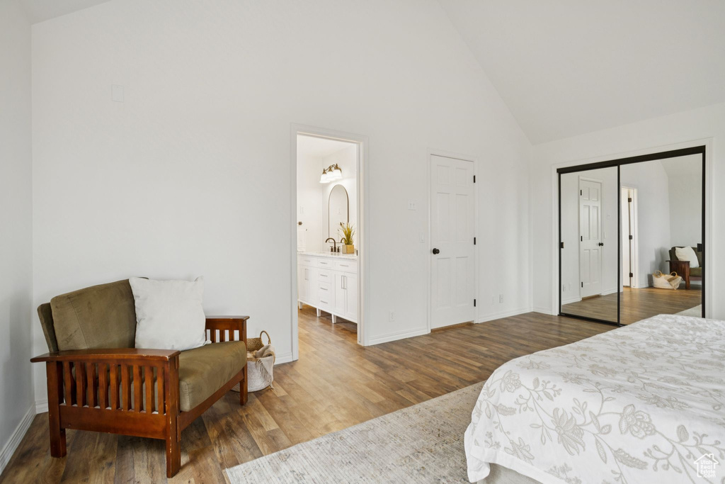 Bedroom featuring wood finished floors, high vaulted ceiling, and ensuite bathroom