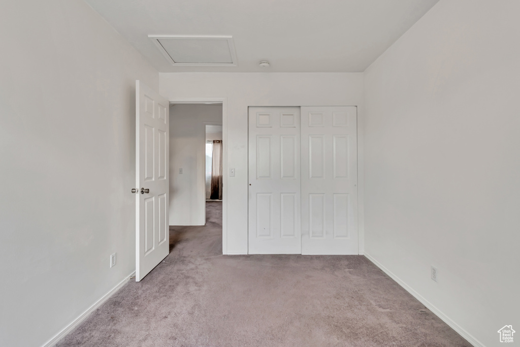 Unfurnished bedroom with carpet floors, a closet, and attic access
