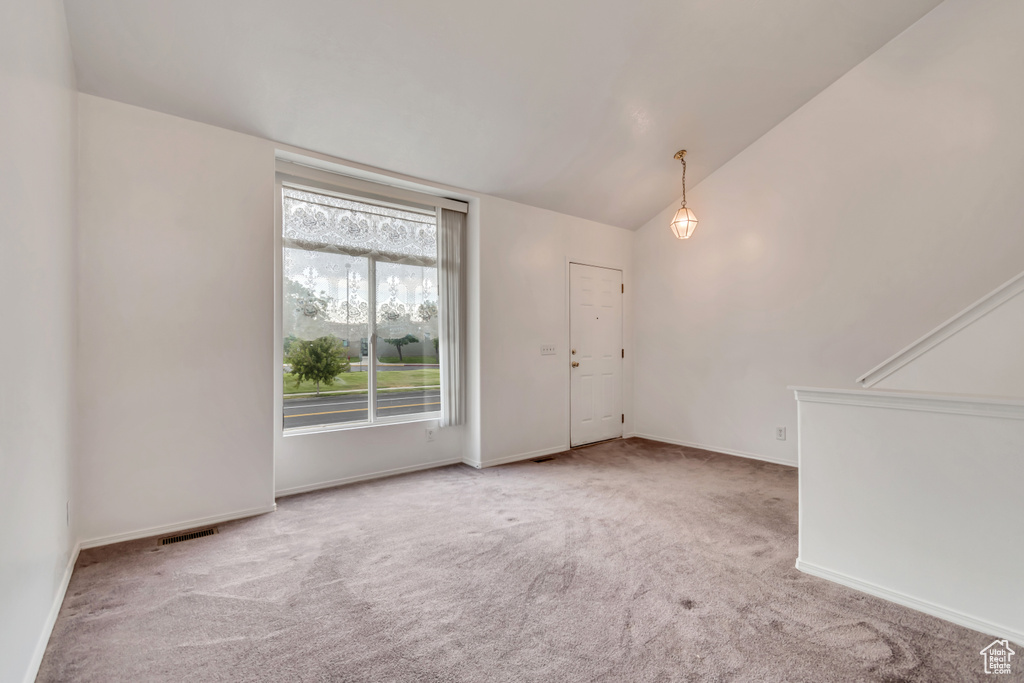 Carpeted empty room with lofted ceiling and baseboards