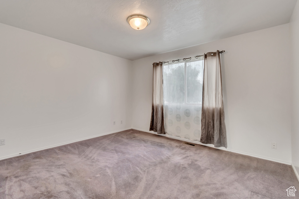 Carpeted empty room featuring baseboards