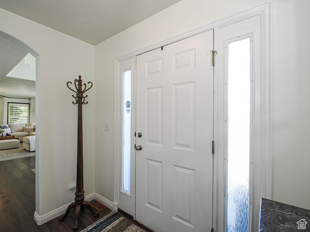 Foyer entrance with arched walkways and dark wood-style flooring