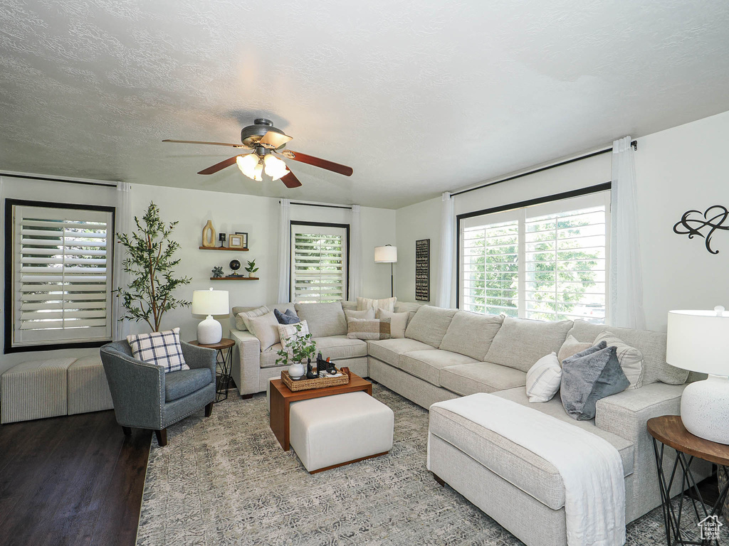 Living room with a ceiling fan, wood finished floors, and a textured ceiling