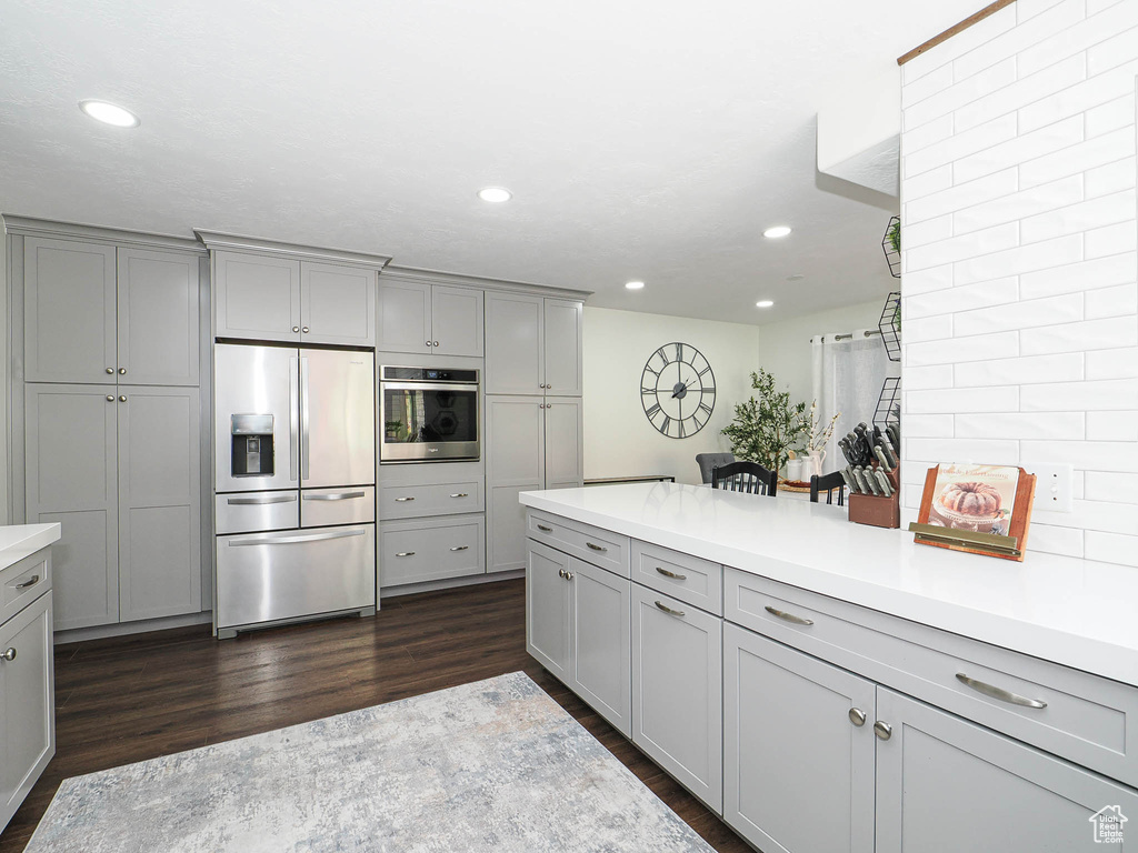 Kitchen featuring stainless steel appliances, gray cabinets, dark wood-type flooring, and recessed lighting