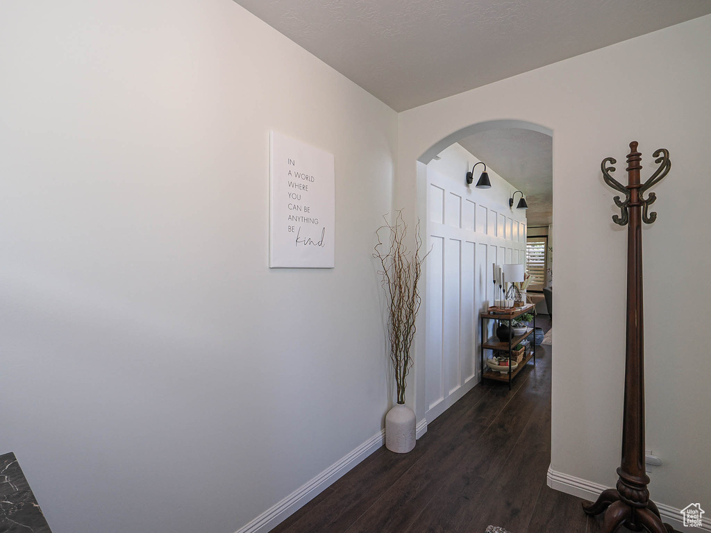 Corridor featuring arched walkways and dark wood-type flooring