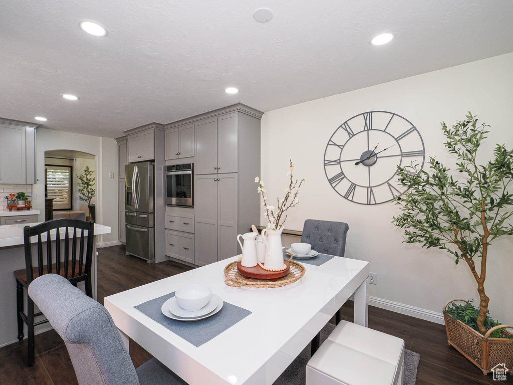Dining room featuring arched walkways, dark wood finished floors, and recessed lighting
