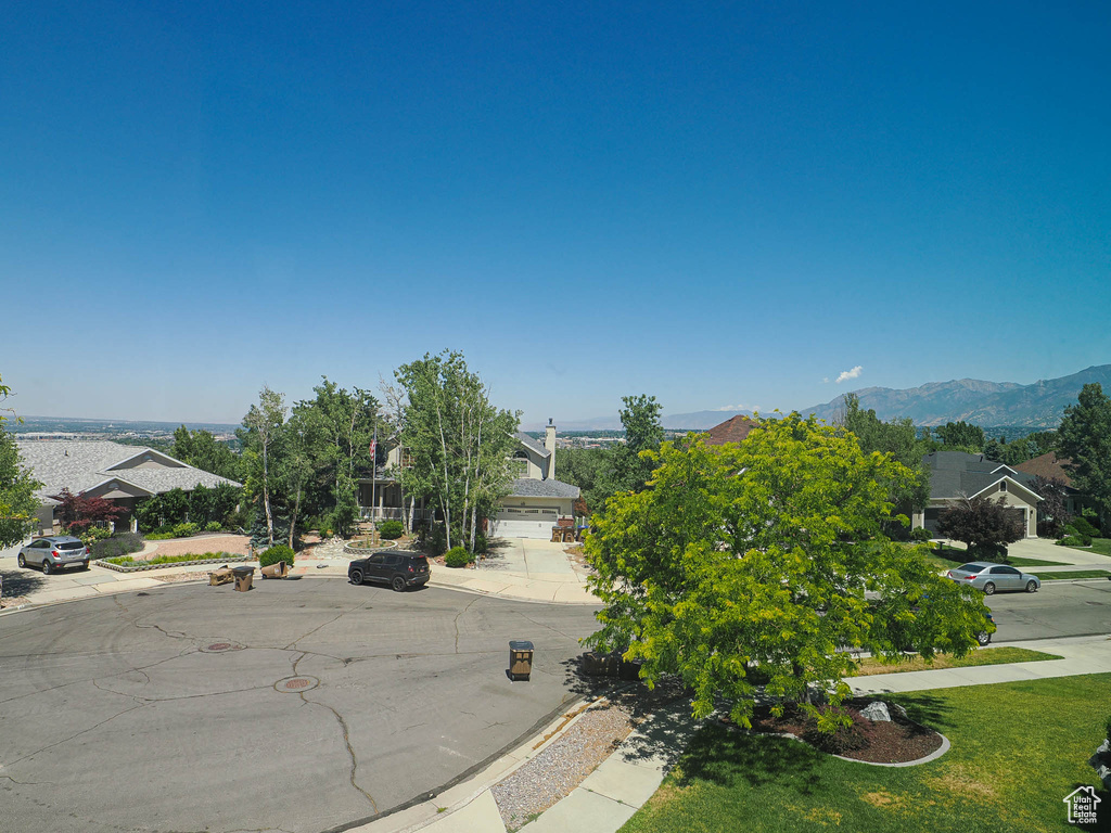 View of asphalt road featuring curbs, sidewalks, and a mountain view