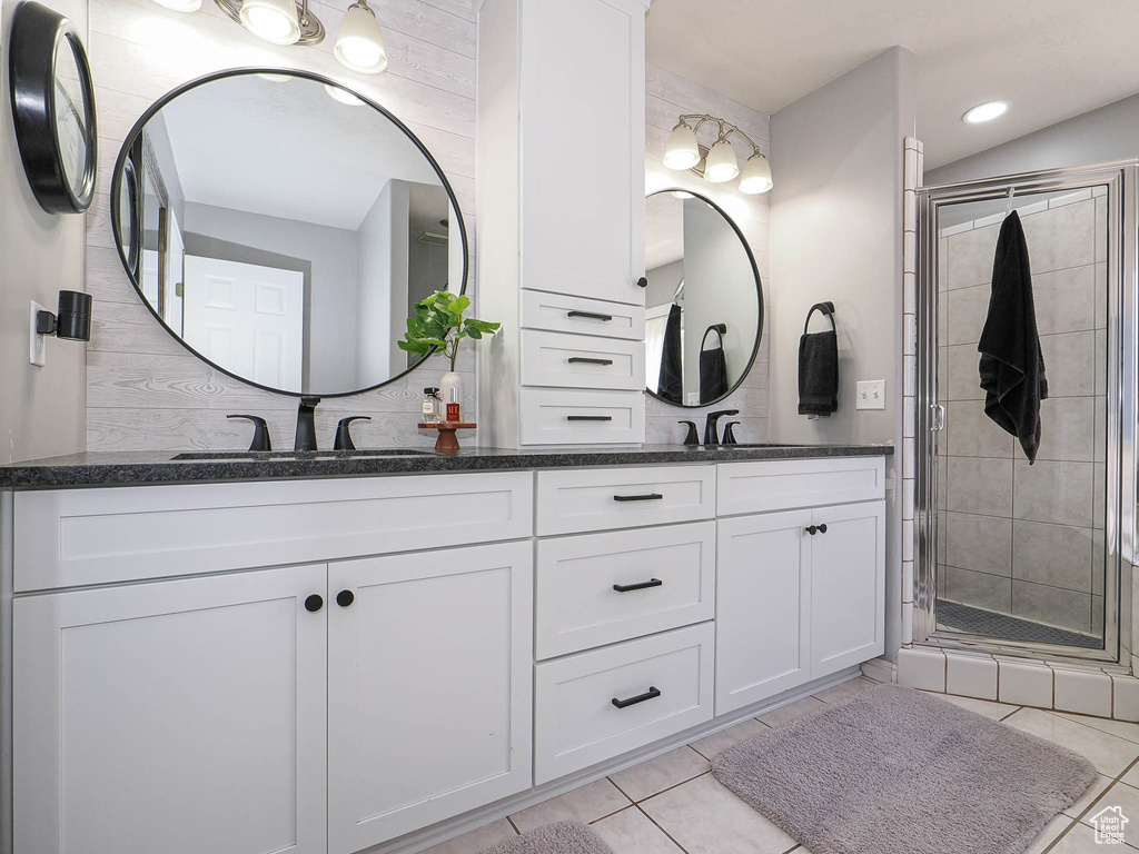 Bathroom featuring double vanity, a shower stall, tile patterned flooring, and recessed lighting