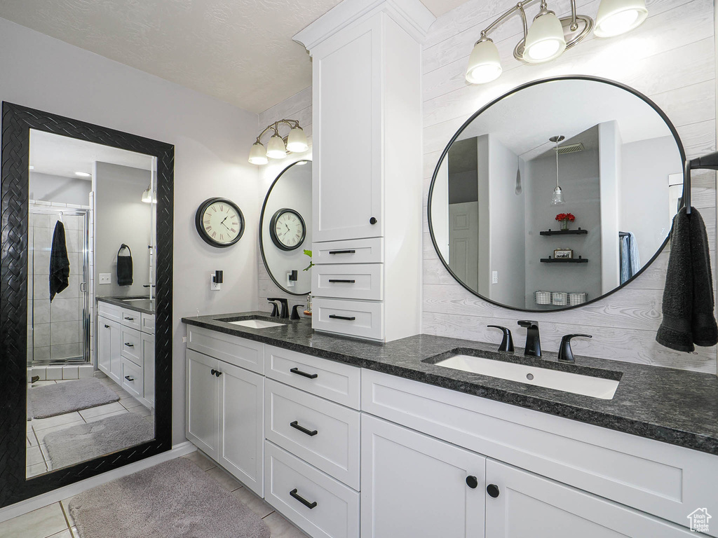 Full bath with double vanity, a stall shower, and tile patterned floors