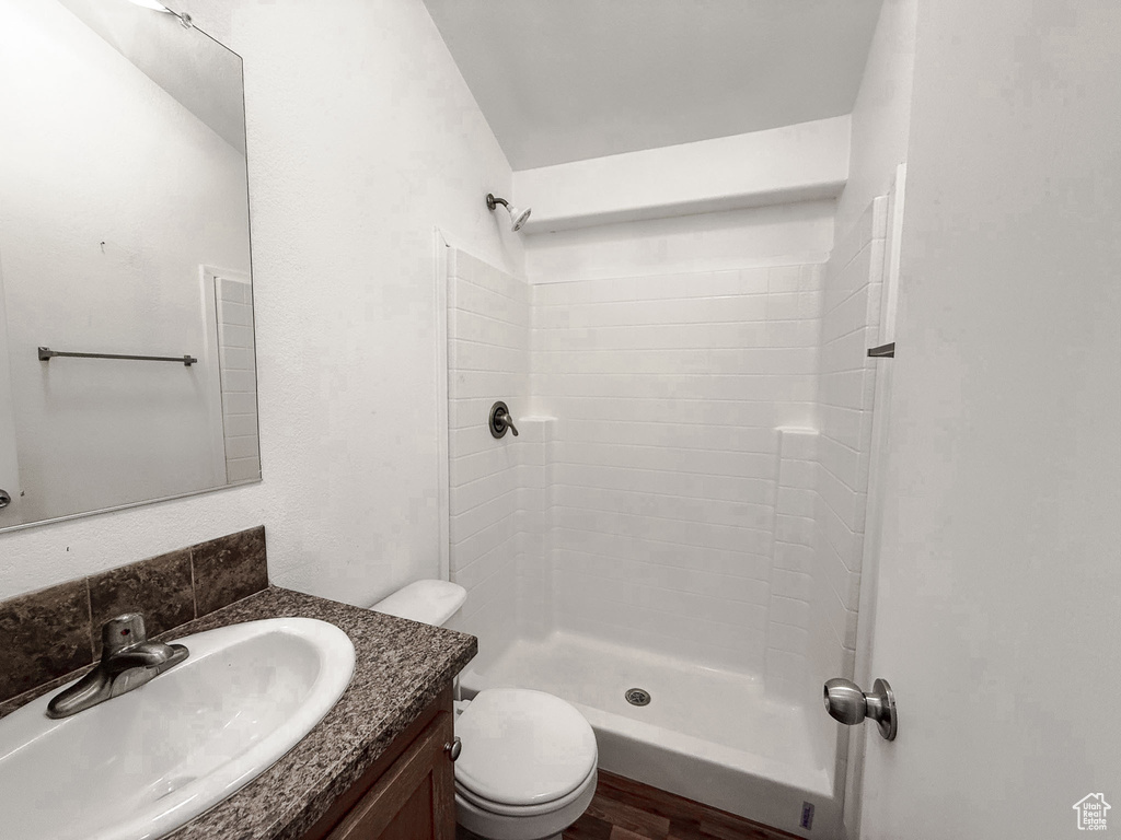 Bathroom featuring vanity, tiled shower, and wood finished floors