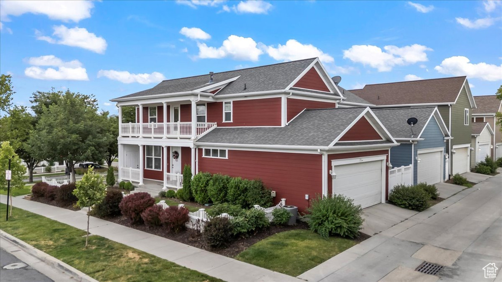 View of front of property featuring a porch, a balcony, roof with shingles, driveway, and a front lawn