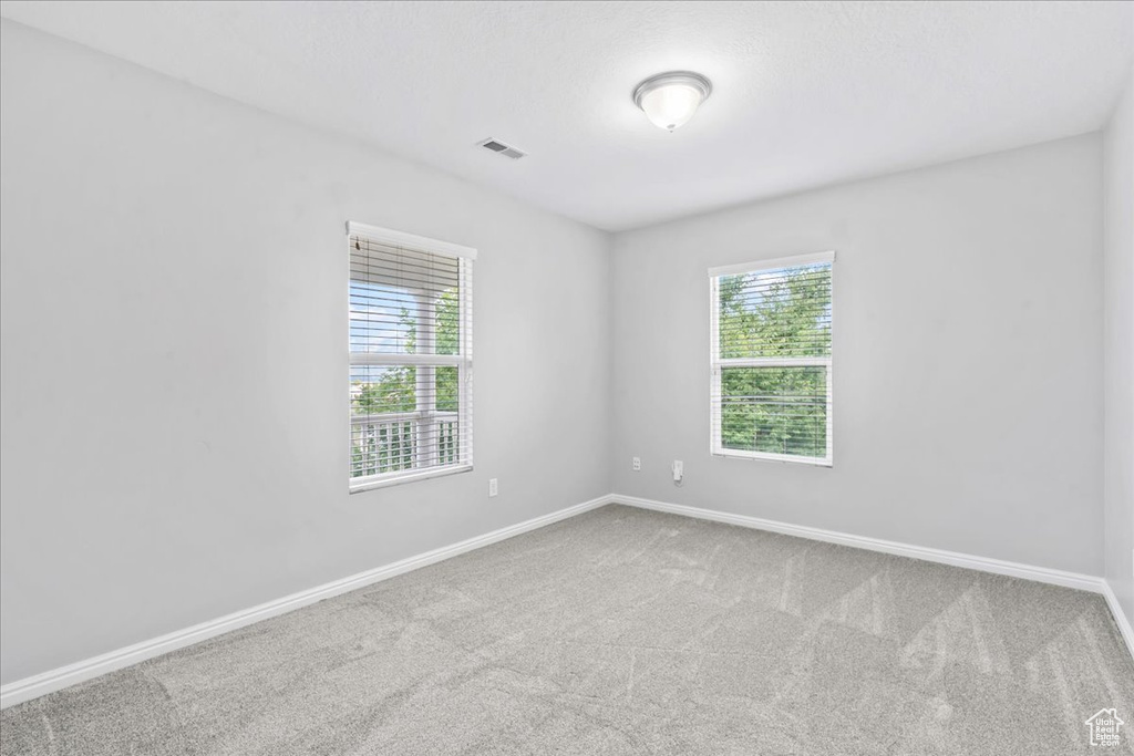 Empty room featuring healthy amount of natural light and carpet
