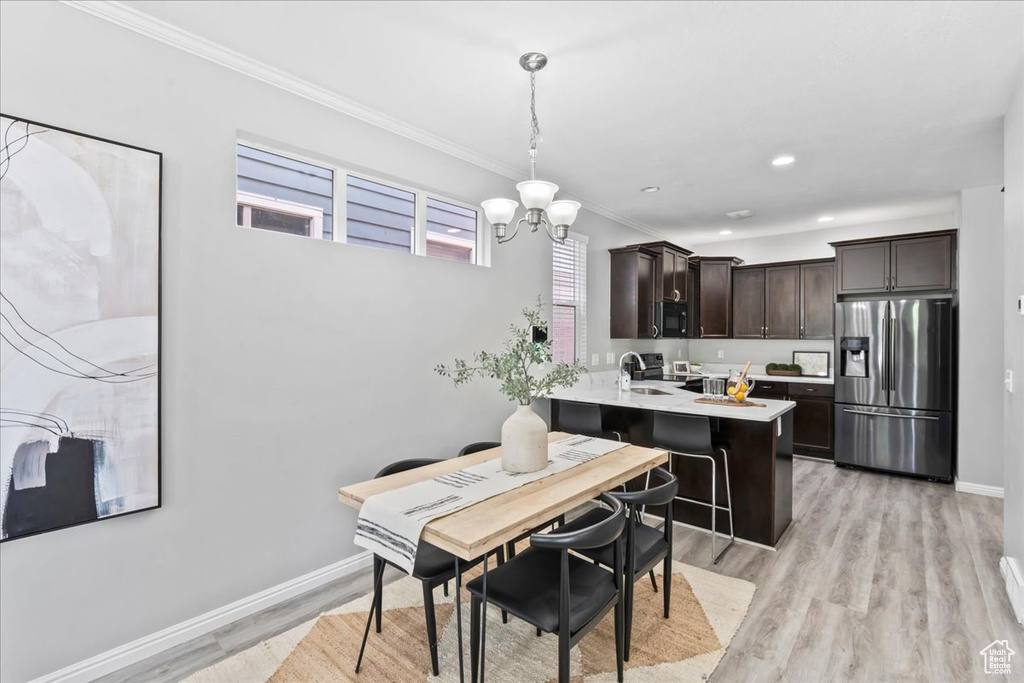 Dining space with ornamental molding, a chandelier, light wood-style floors, and recessed lighting