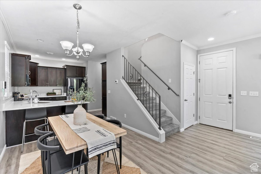 Dining room featuring a chandelier, light wood-type flooring, stairs, crown molding, and recessed lighting