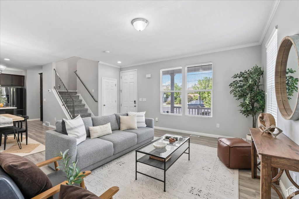 Living area featuring light wood finished floors, stairs, ornamental molding, and recessed lighting