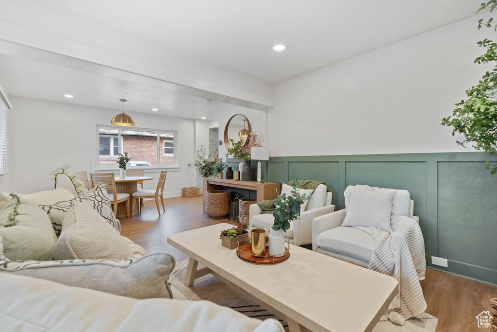 Living room featuring wood finished floors, a decorative wall, recessed lighting, and wainscoting