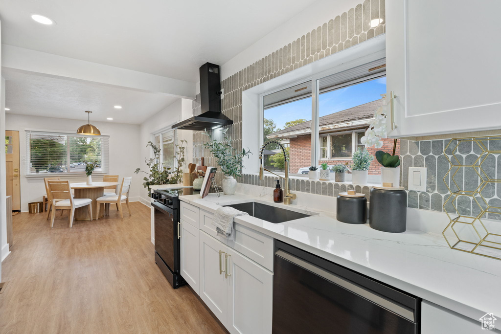 Kitchen with wall chimney range hood, black range with electric cooktop, dishwasher, white cabinetry, and recessed lighting