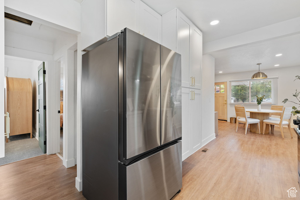Kitchen featuring freestanding refrigerator, light wood-style flooring, white cabinetry, recessed lighting, and hanging light fixtures