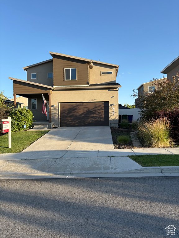 View of front of property featuring concrete driveway, a garage, and stucco siding