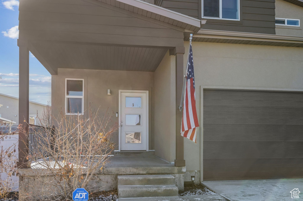Property entrance featuring stucco siding and an attached garage