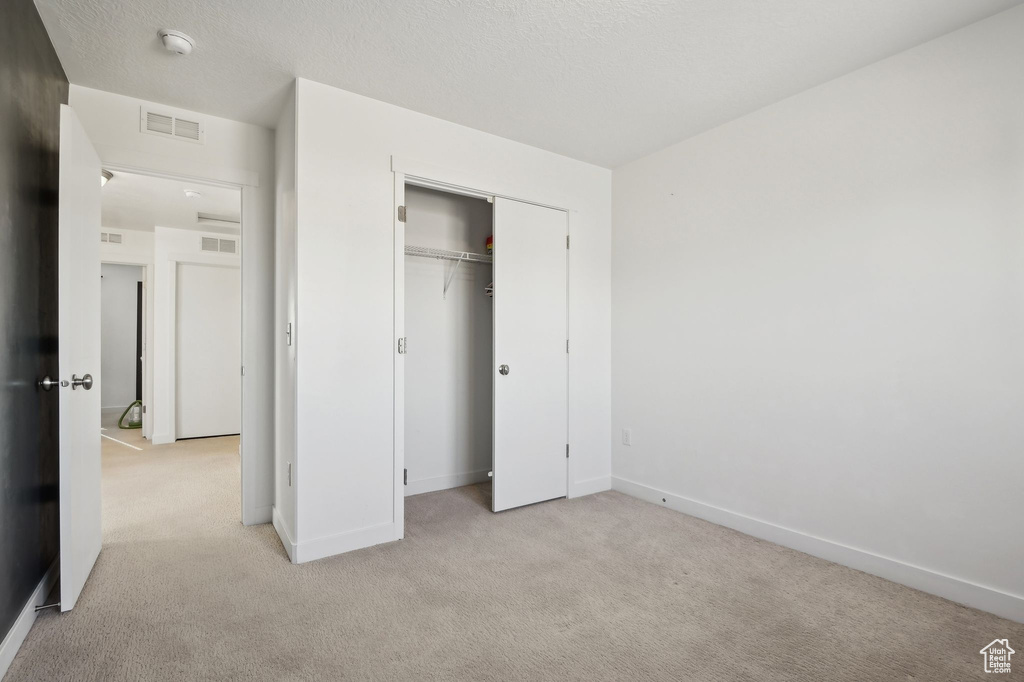 Unfurnished bedroom featuring light carpet and a closet