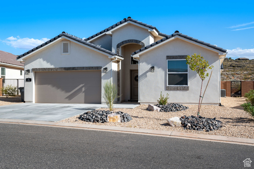 Mediterranean / spanish-style home with a garage, stucco siding, driveway, and a tile roof