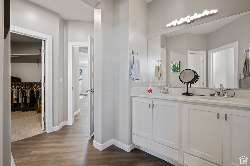 Bathroom with double vanity, wood finished floors, and a walk in closet