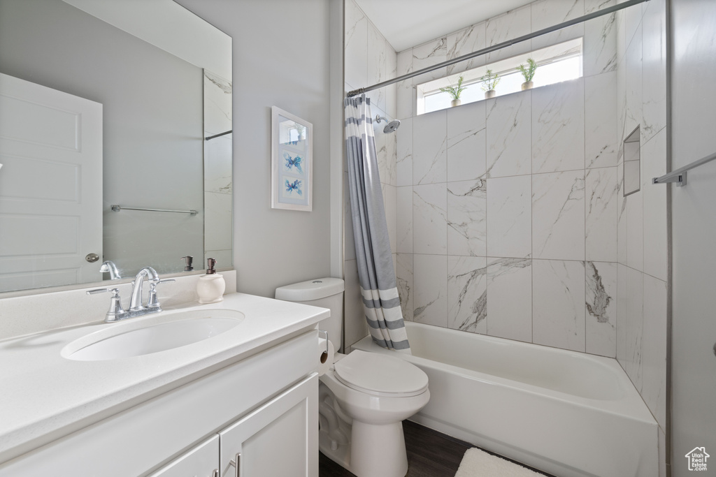 Bathroom with vanity, shower / bath combo with shower curtain, and wood finished floors