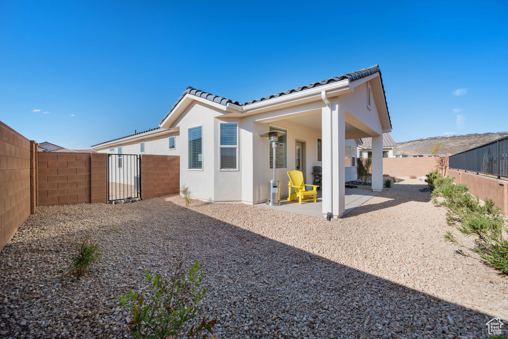 Rear view of property with a patio area, a fenced backyard, stucco siding, and a tiled roof